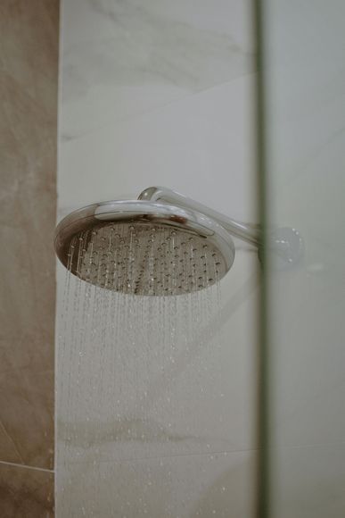 A close up of a shower head in a bathroom with water coming out of it.