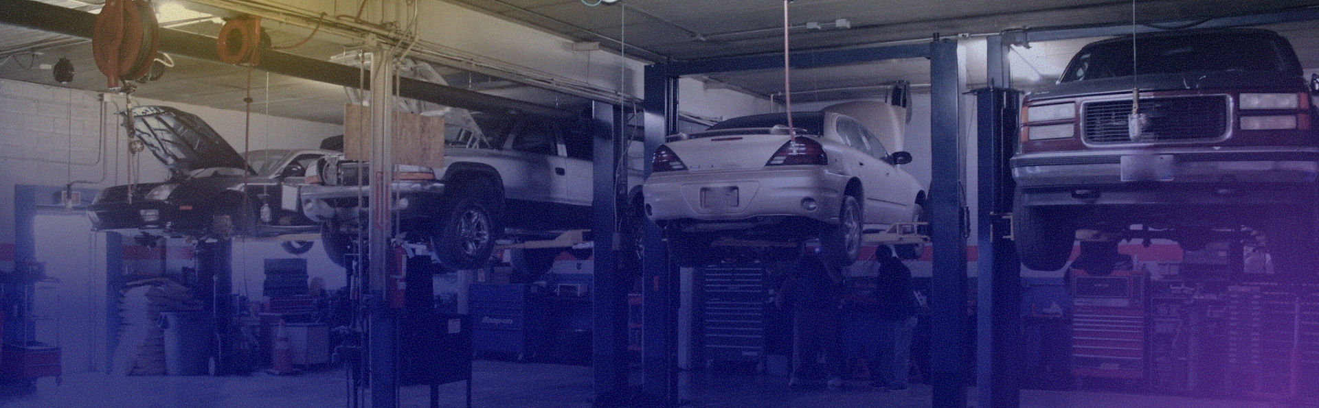 A bunch of cars are sitting on lifts in a garage. | Sunset Tire and Auto Repair