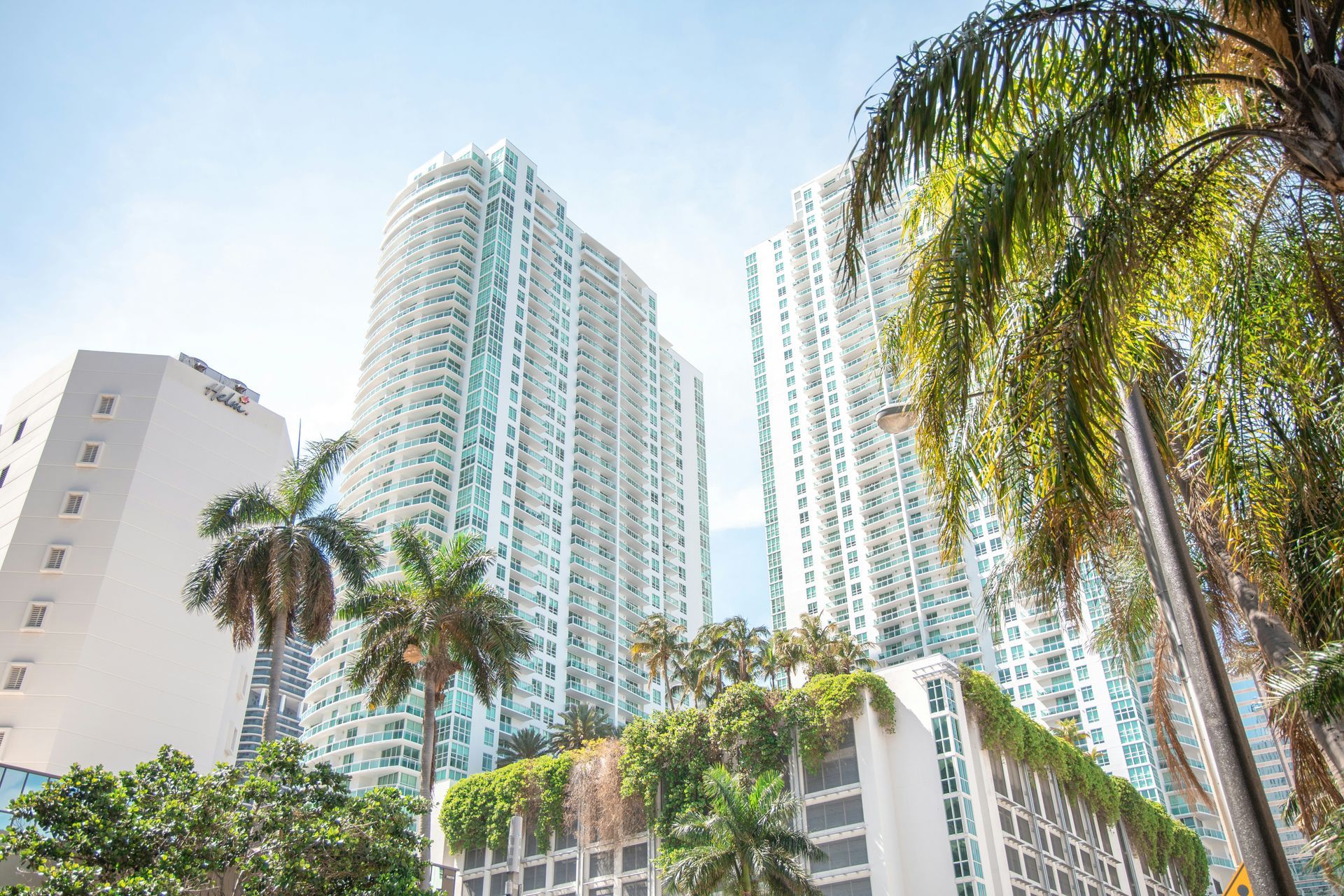 Tall white buildings and palm trees against a bright blue sky in Miami.