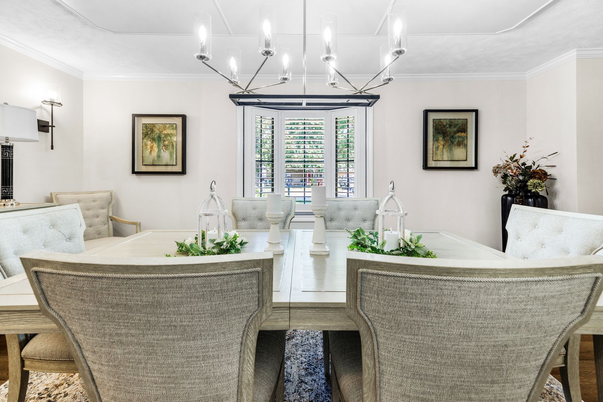 Elegant dining room with chandelier, table set for dining, and shuttered window.