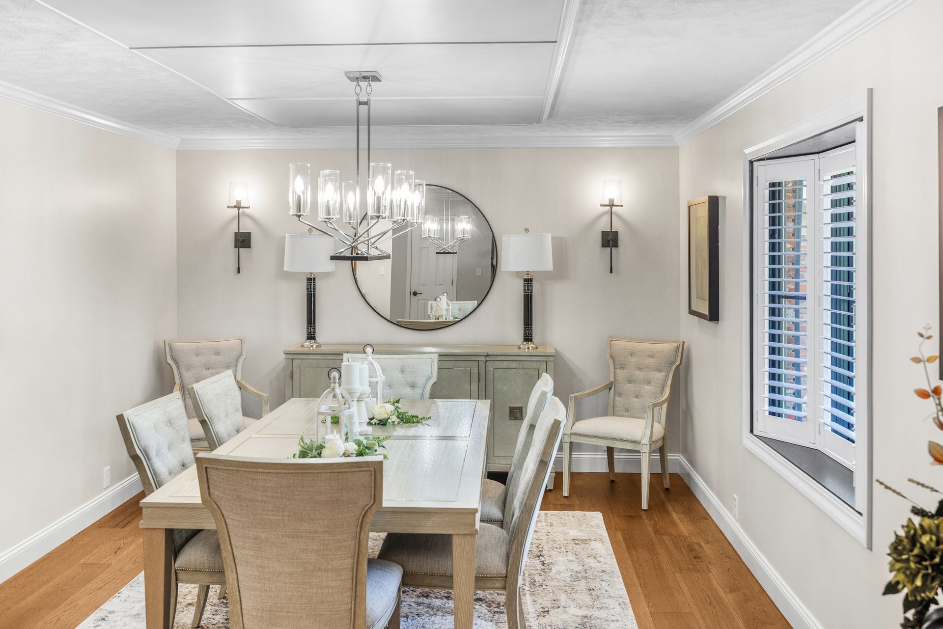 Formal dining room with wood floors, light walls, and a table set for dining.