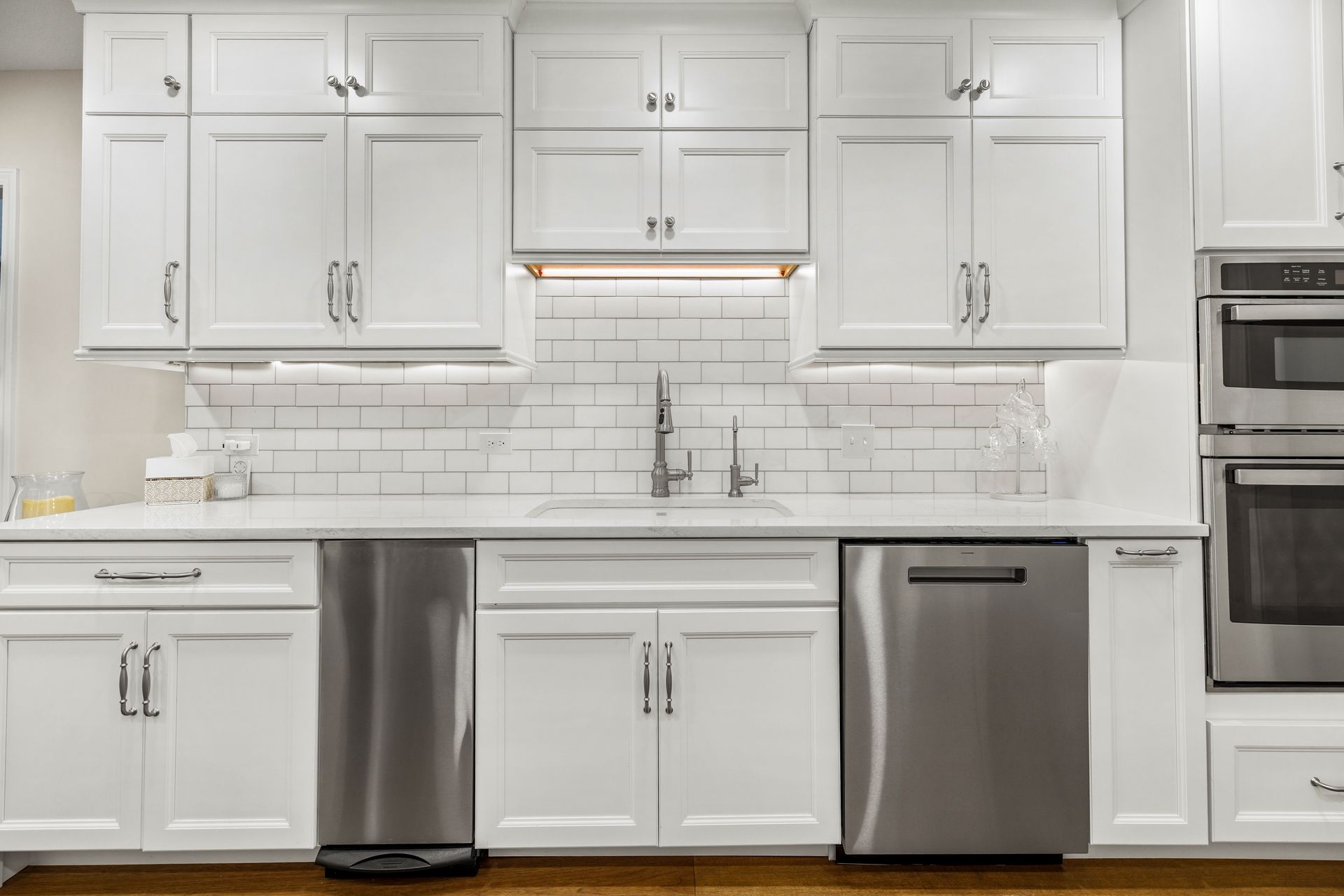 White kitchen with stainless steel appliances, white cabinets, and white subway tile backsplash.