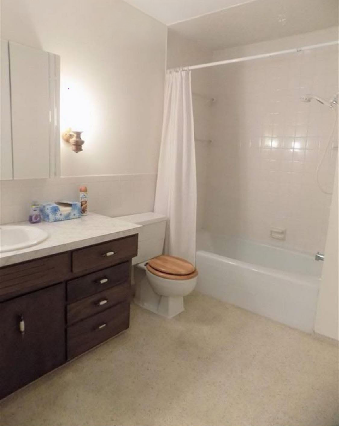 Bathroom with a white tub, toilet, and vanity with dark brown cabinets.