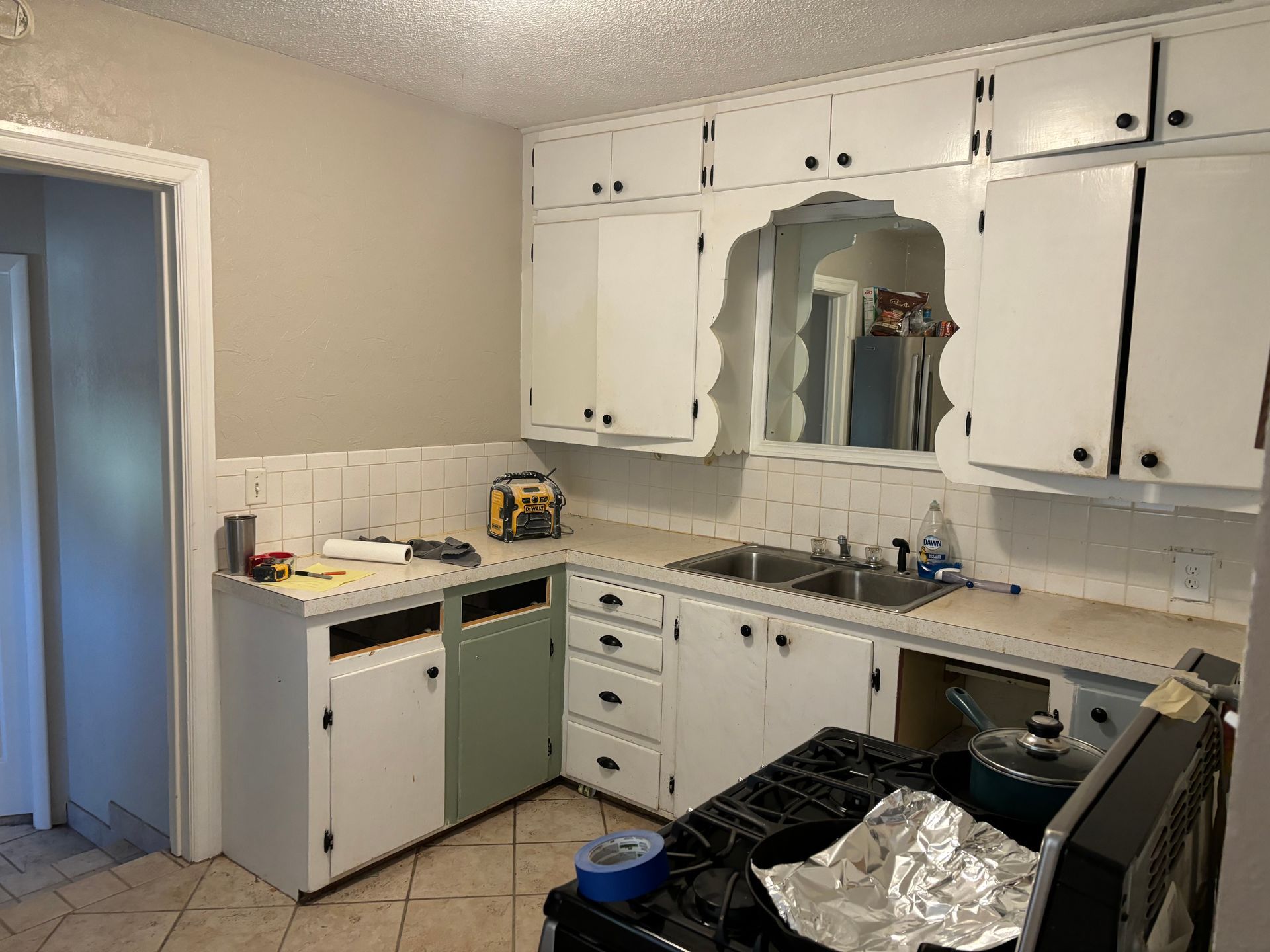 Kitchen with white cabinets, green lower cabinet door, and stainless steel sink.