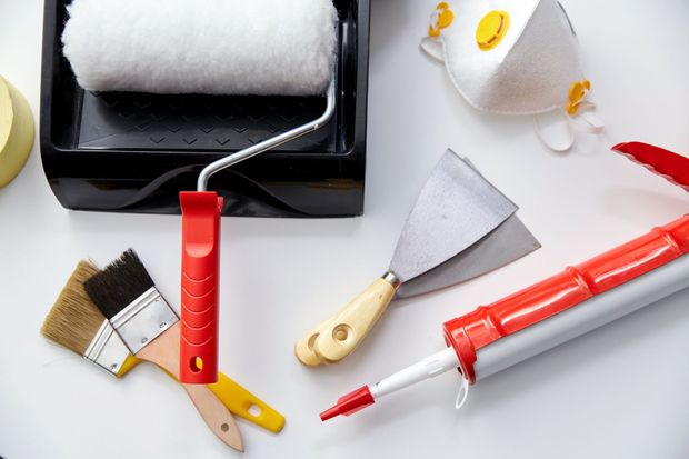 Paint supplies: paint roller, tray, brushes, putty knife, caulk gun, and respirator mask.