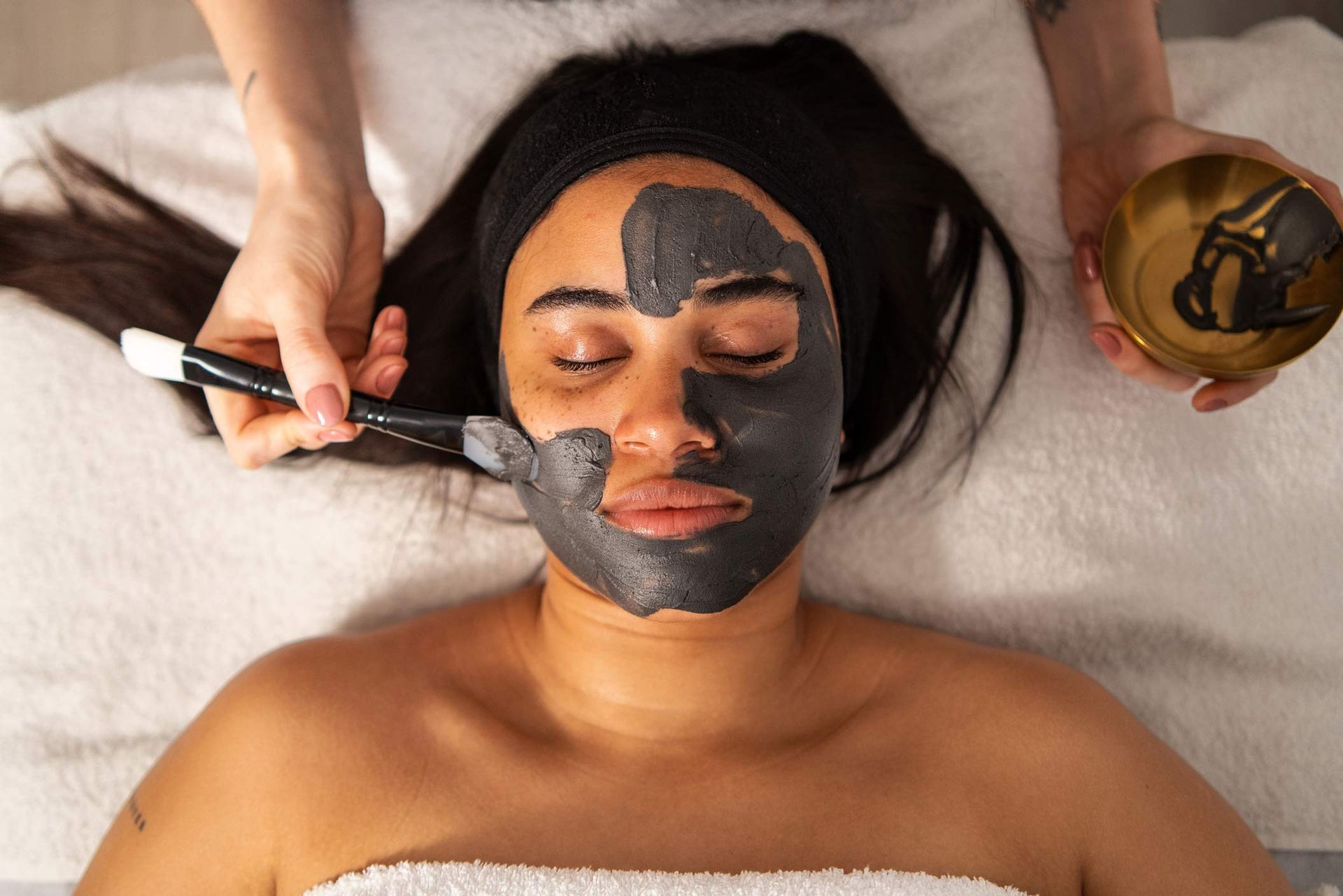 Top view of a woman receiving a facial spa treatment mask in the spa.