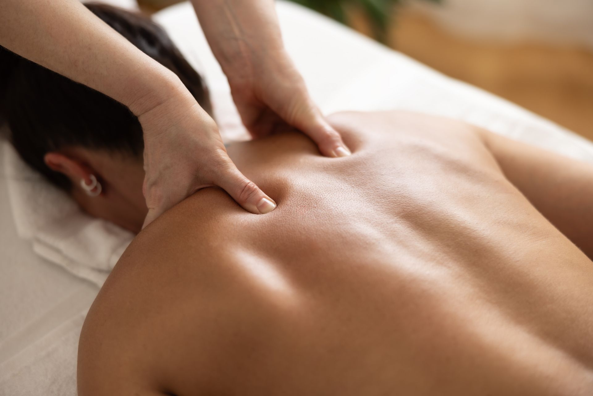A masseuse is massaging the back of a woman.