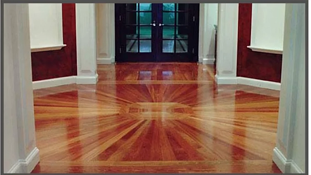 Wooden floor hallway with a burst pattern and a dark double door.