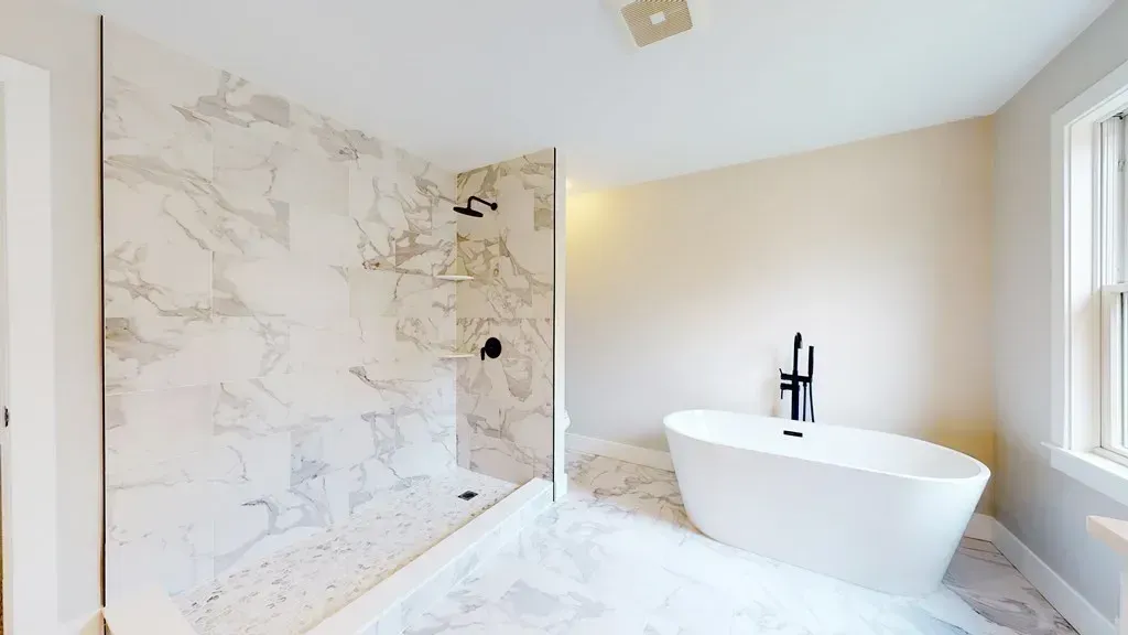 A bathroom with a tub , shower , and window.