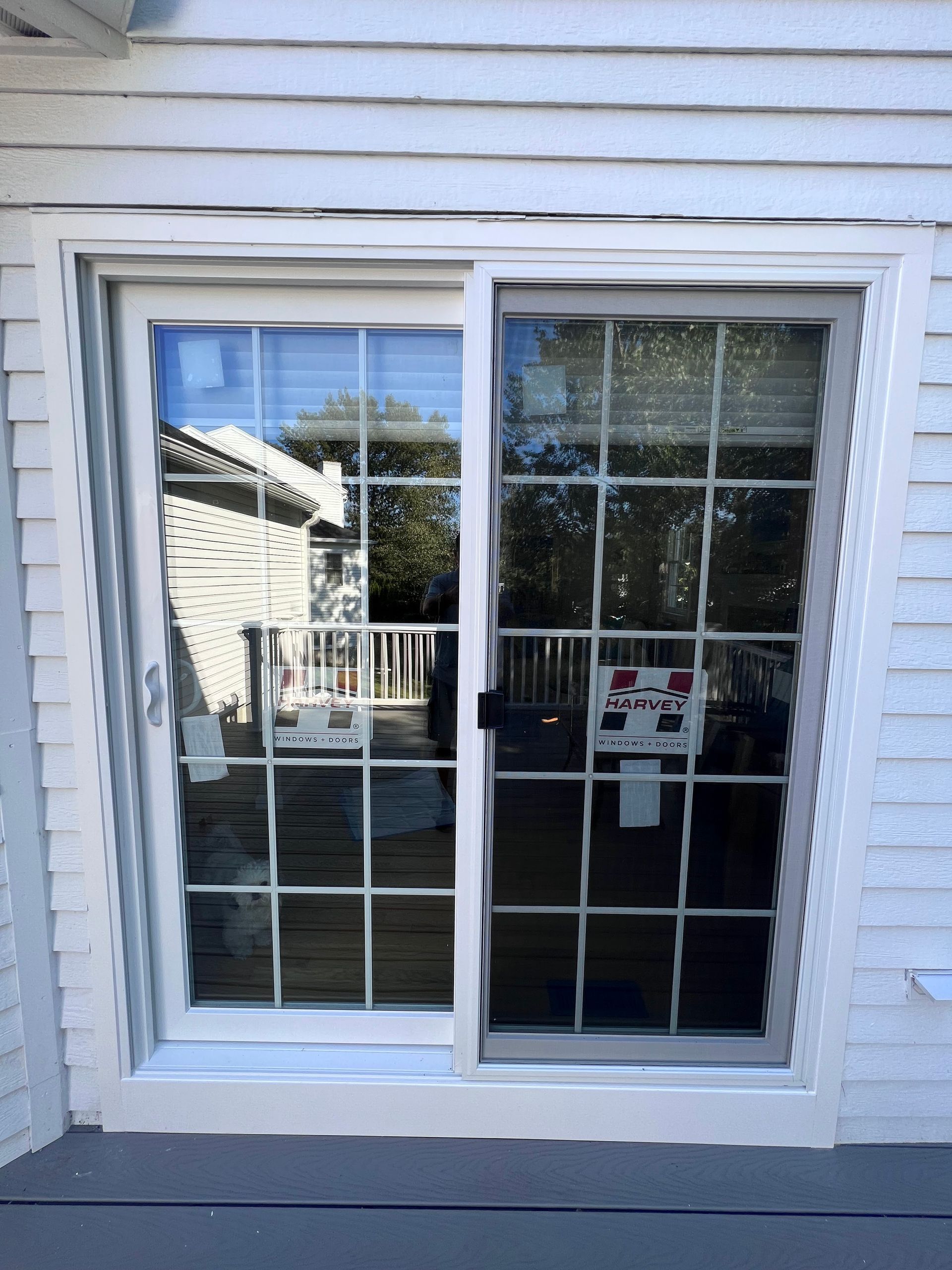 A white house with a sliding glass door leading to a deck.