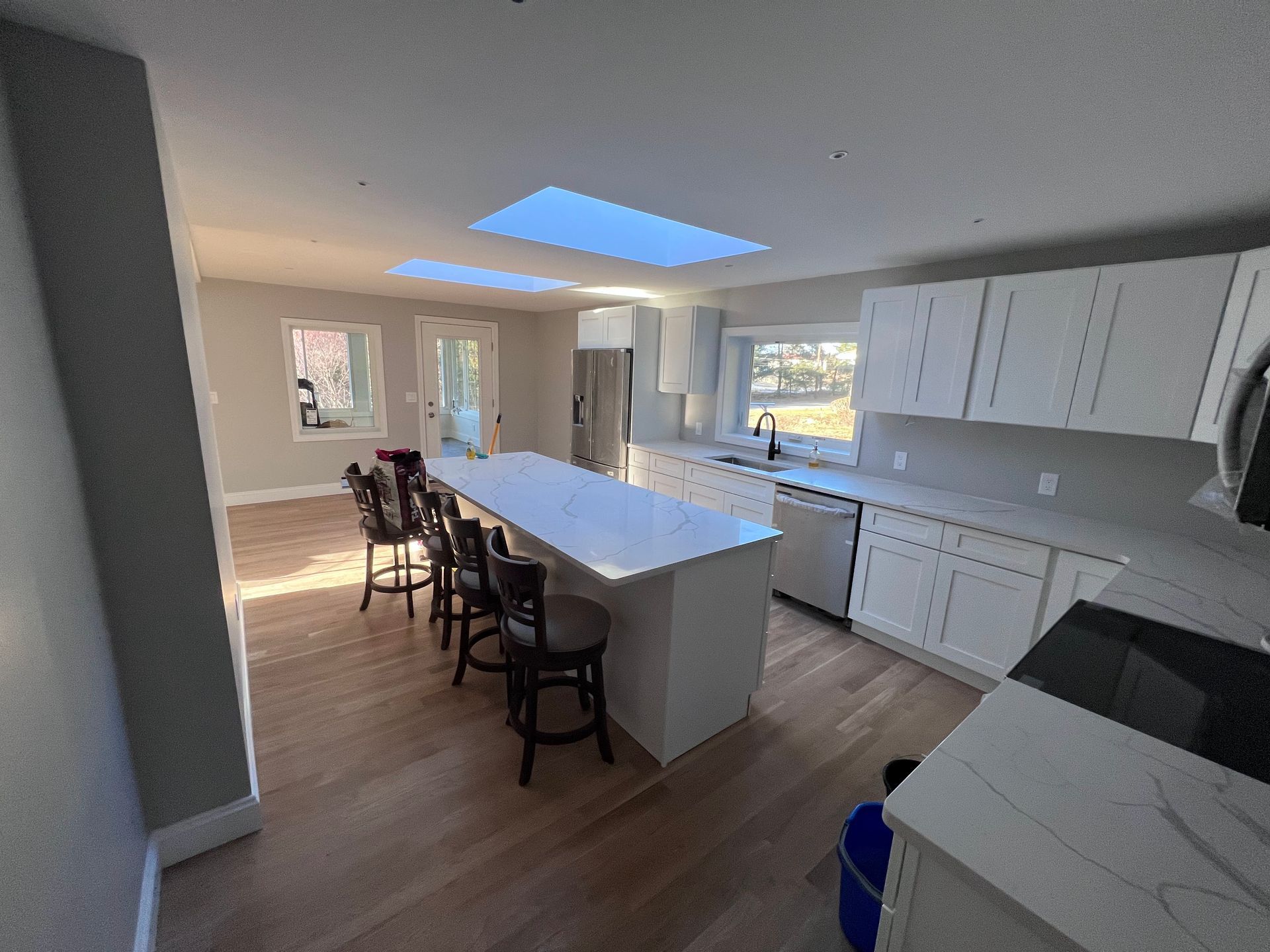 A kitchen with white cabinets , stainless steel appliances and a large island.