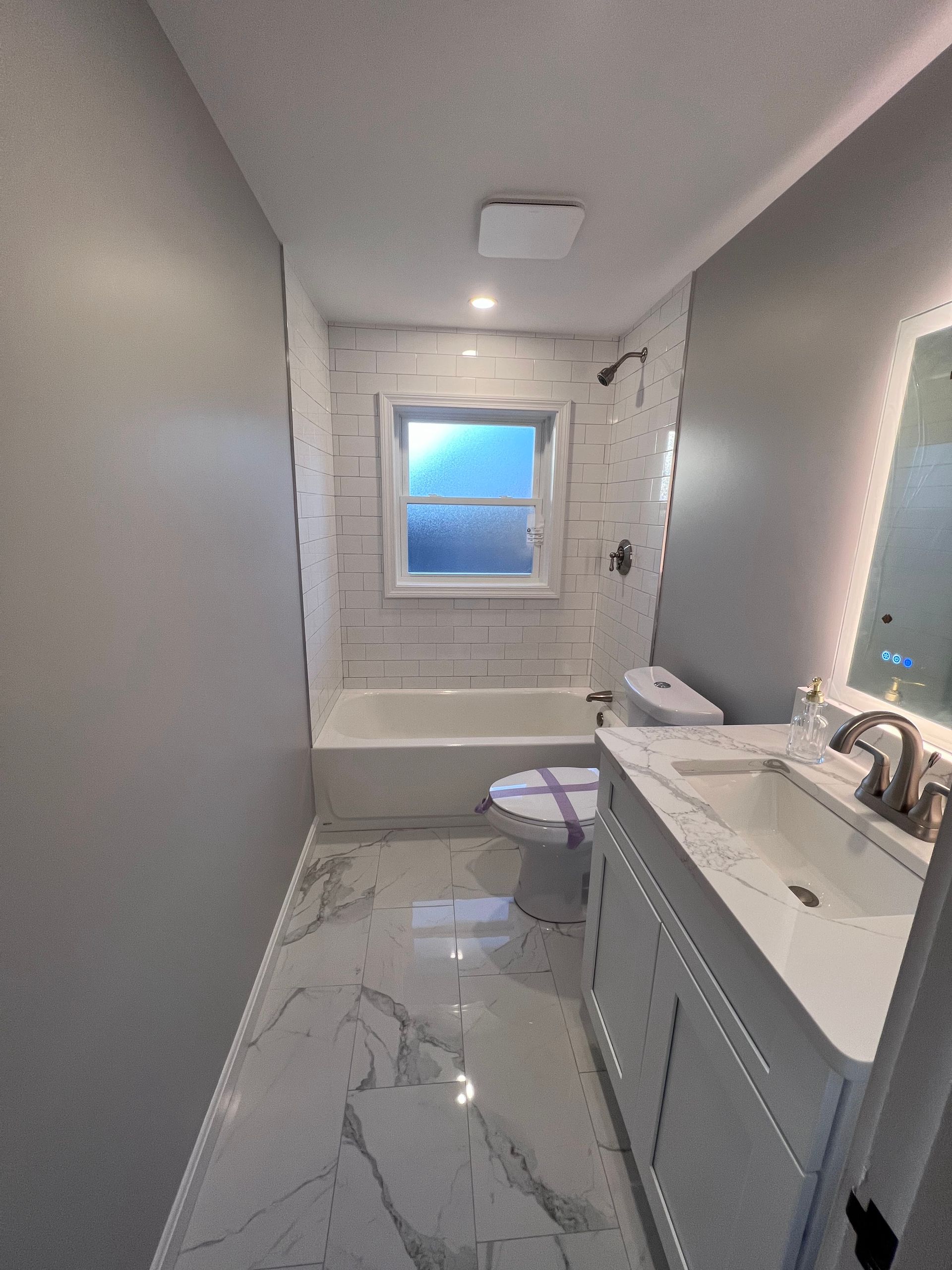 A bathroom with a sink , toilet , tub and mirror.