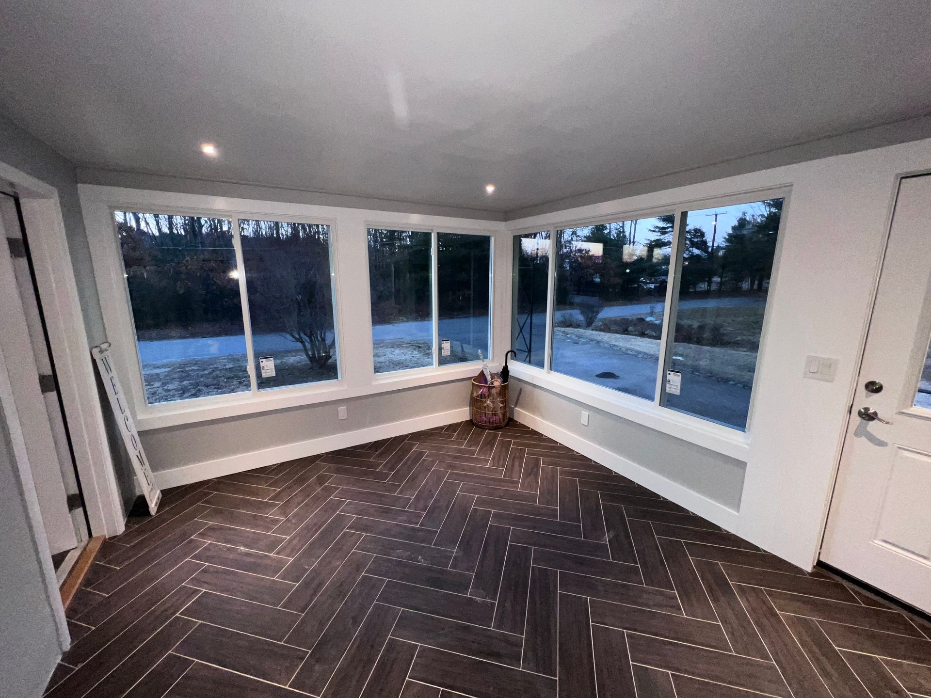 A room with a lot of windows and a herringbone floor.