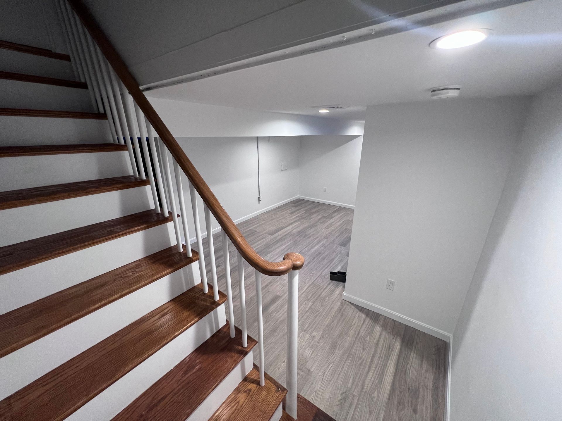 A staircase in a basement with wooden steps and a wooden railing.