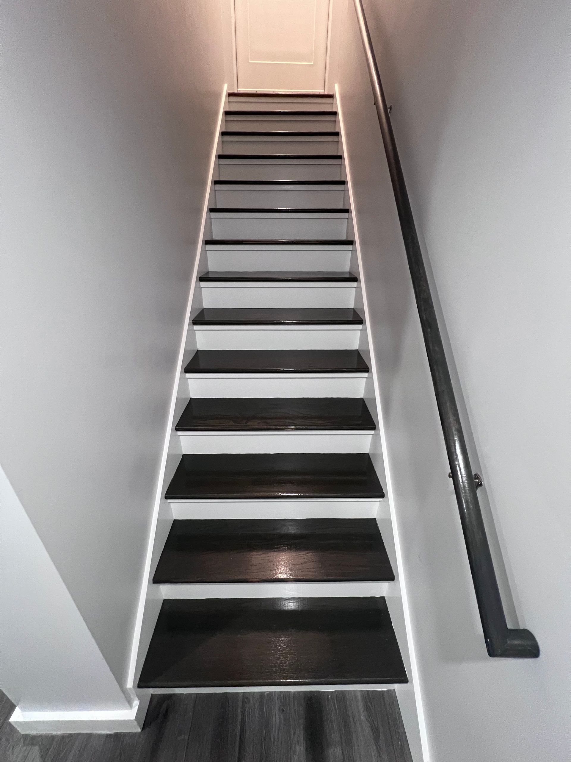 A staircase with black steps and a white railing in a house.
