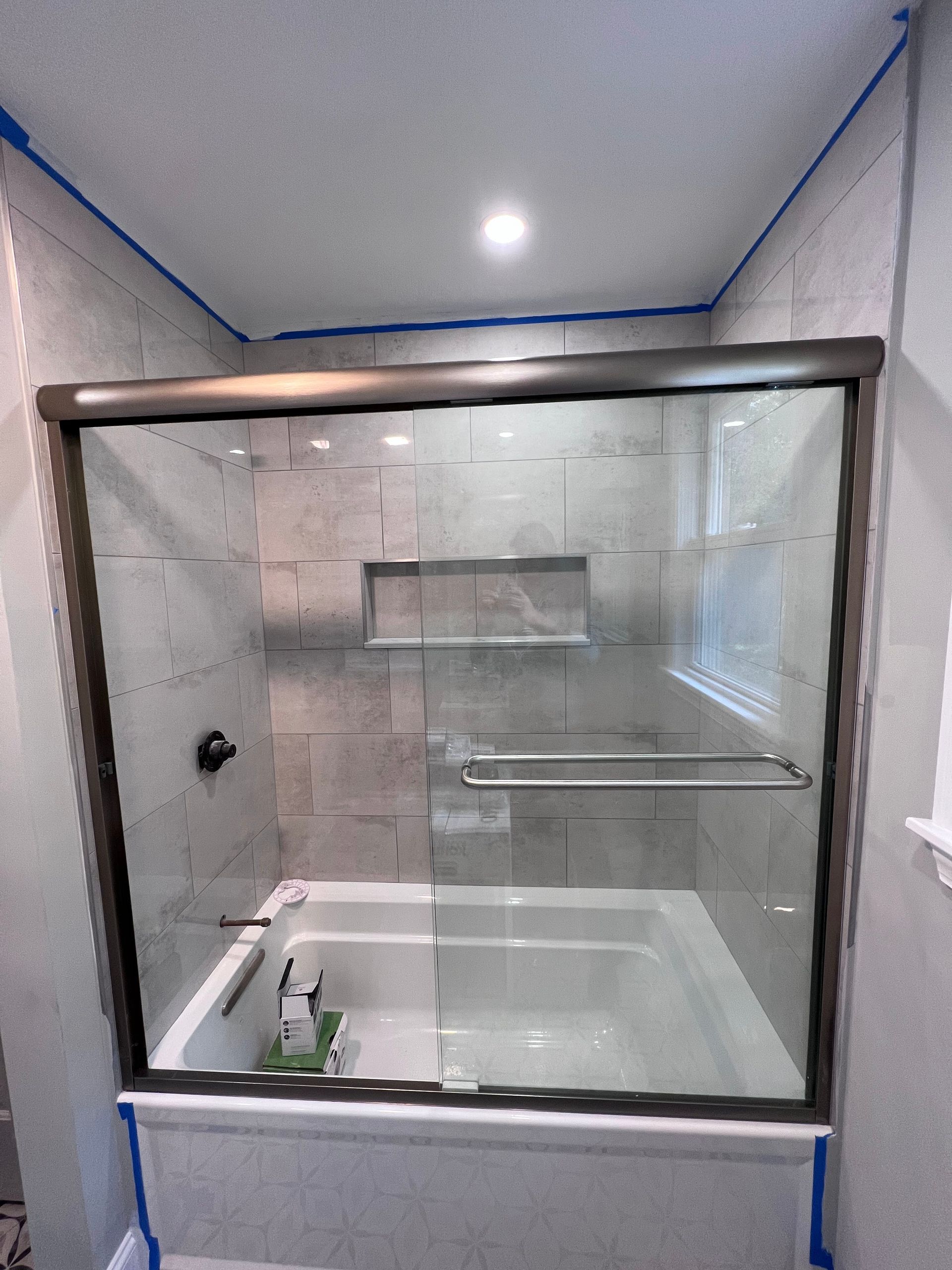 A bathroom with a bathtub and a glass shower door