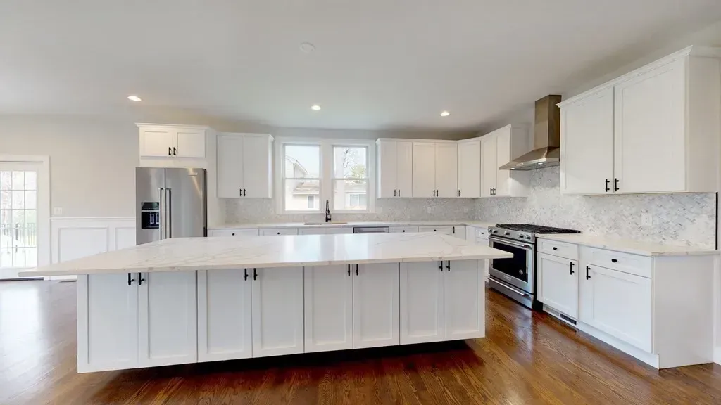 A kitchen with white cabinets , stainless steel appliances , and a large island.