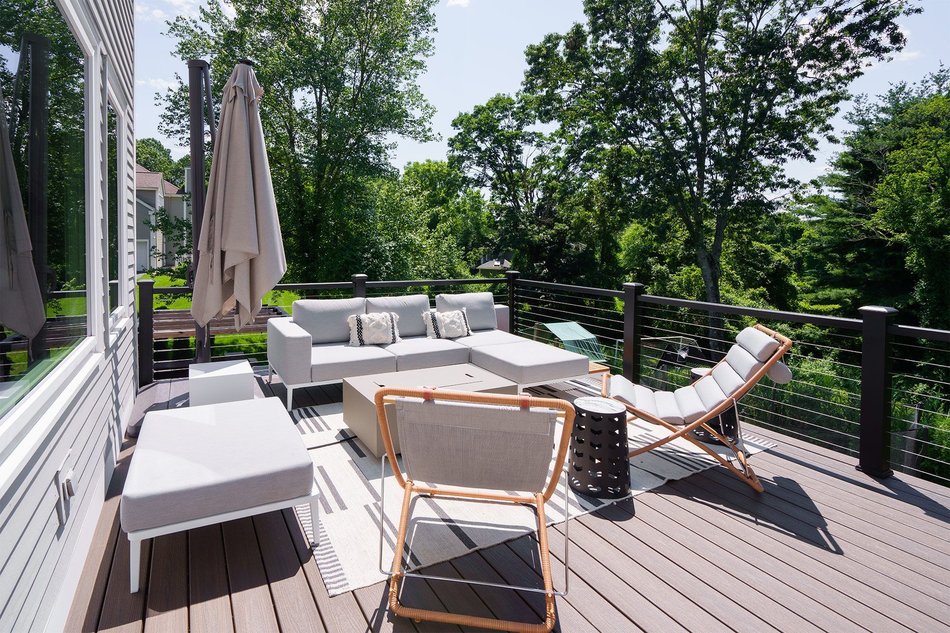A deck with a couch , chairs , and umbrellas on it.