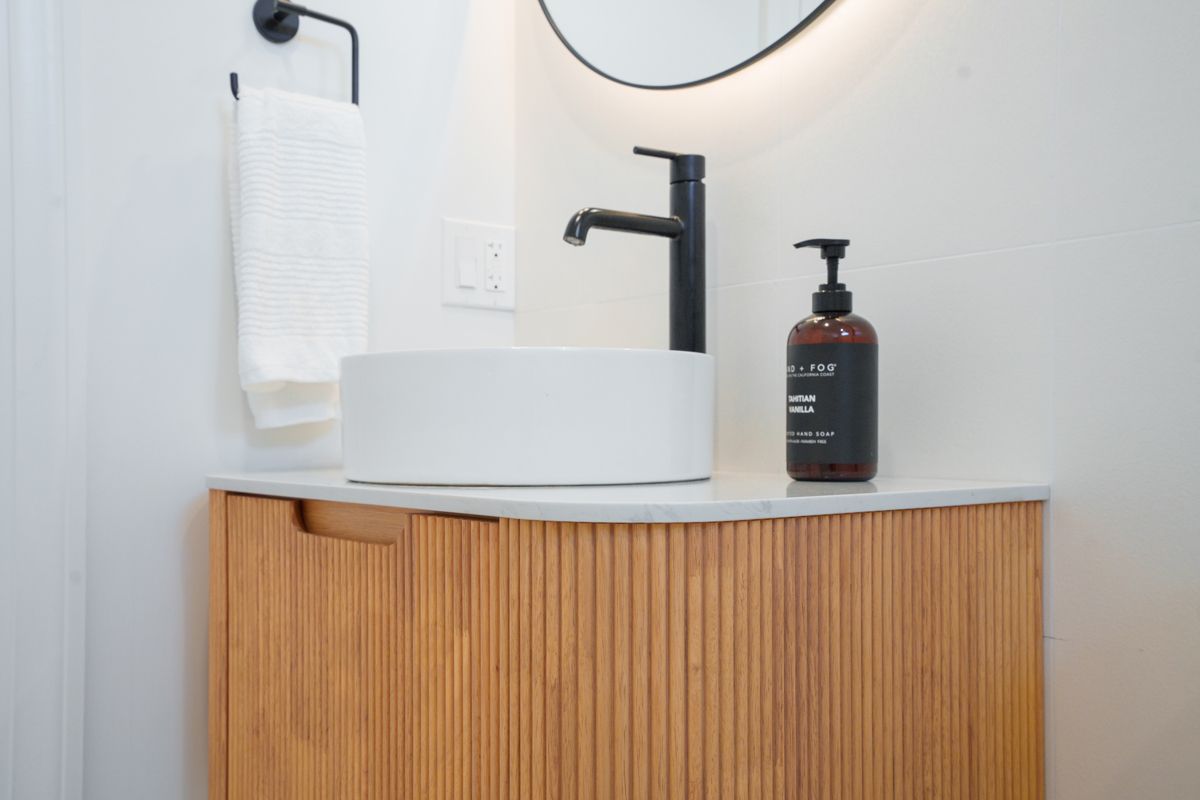 A bathroom with a sink , mirror and soap dispenser.