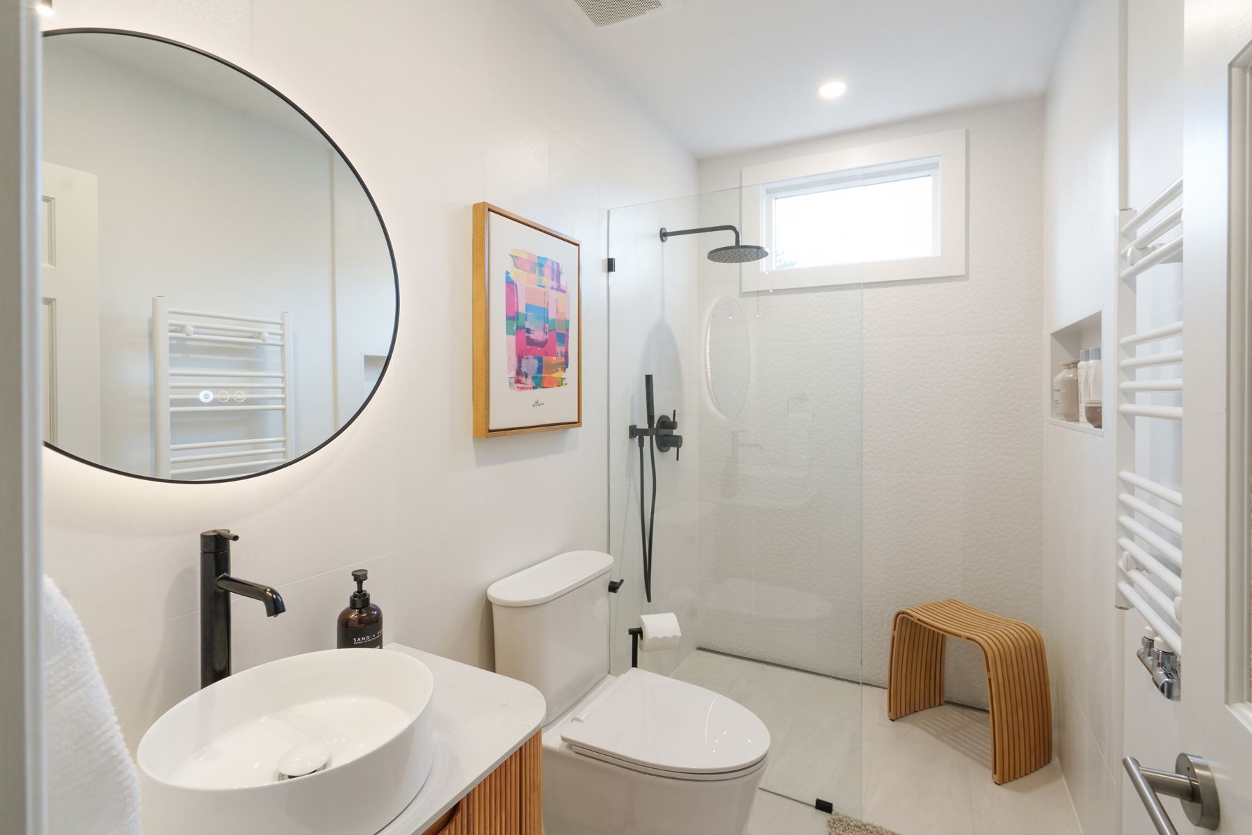 A bathroom with a toilet , sink , mirror and shower.