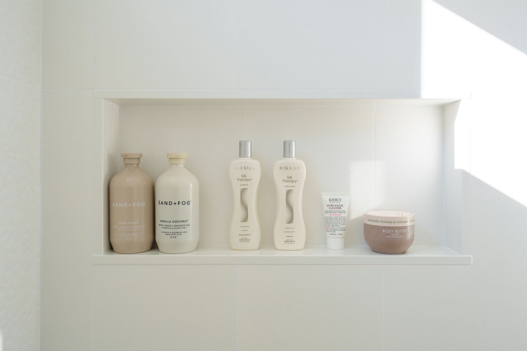 A shelf with bottles of shampoo and conditioner on it