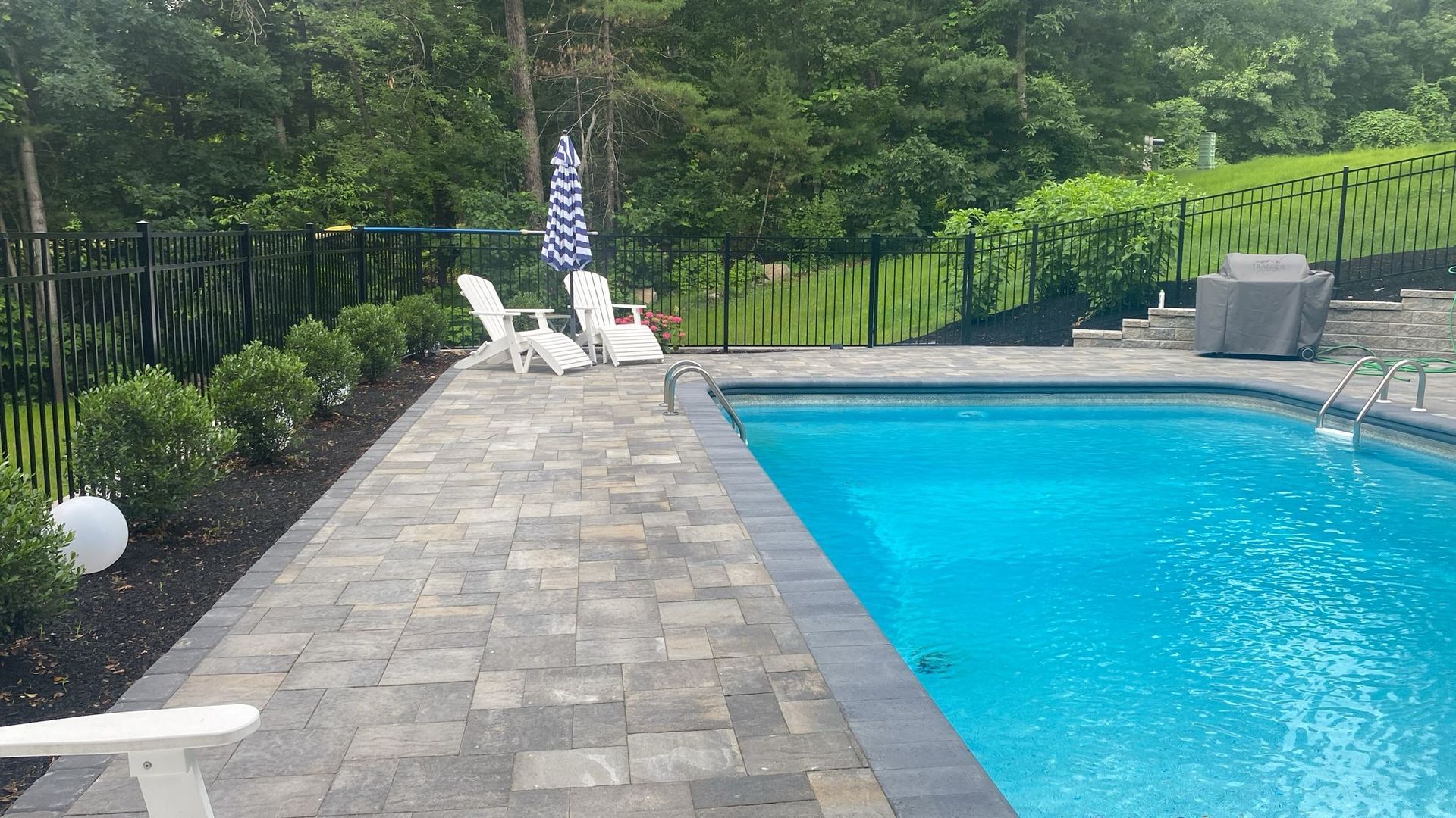 A large swimming pool surrounded by chairs and a fence