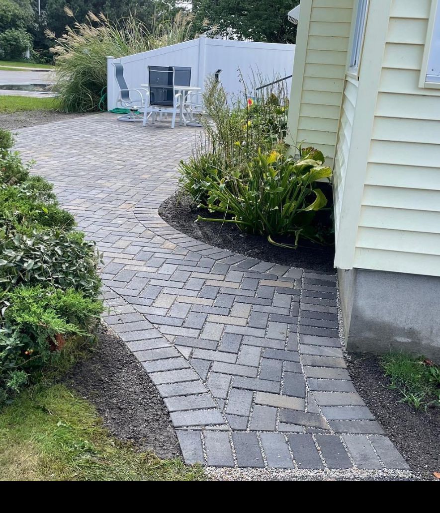 A brick walkway leading to a white house.