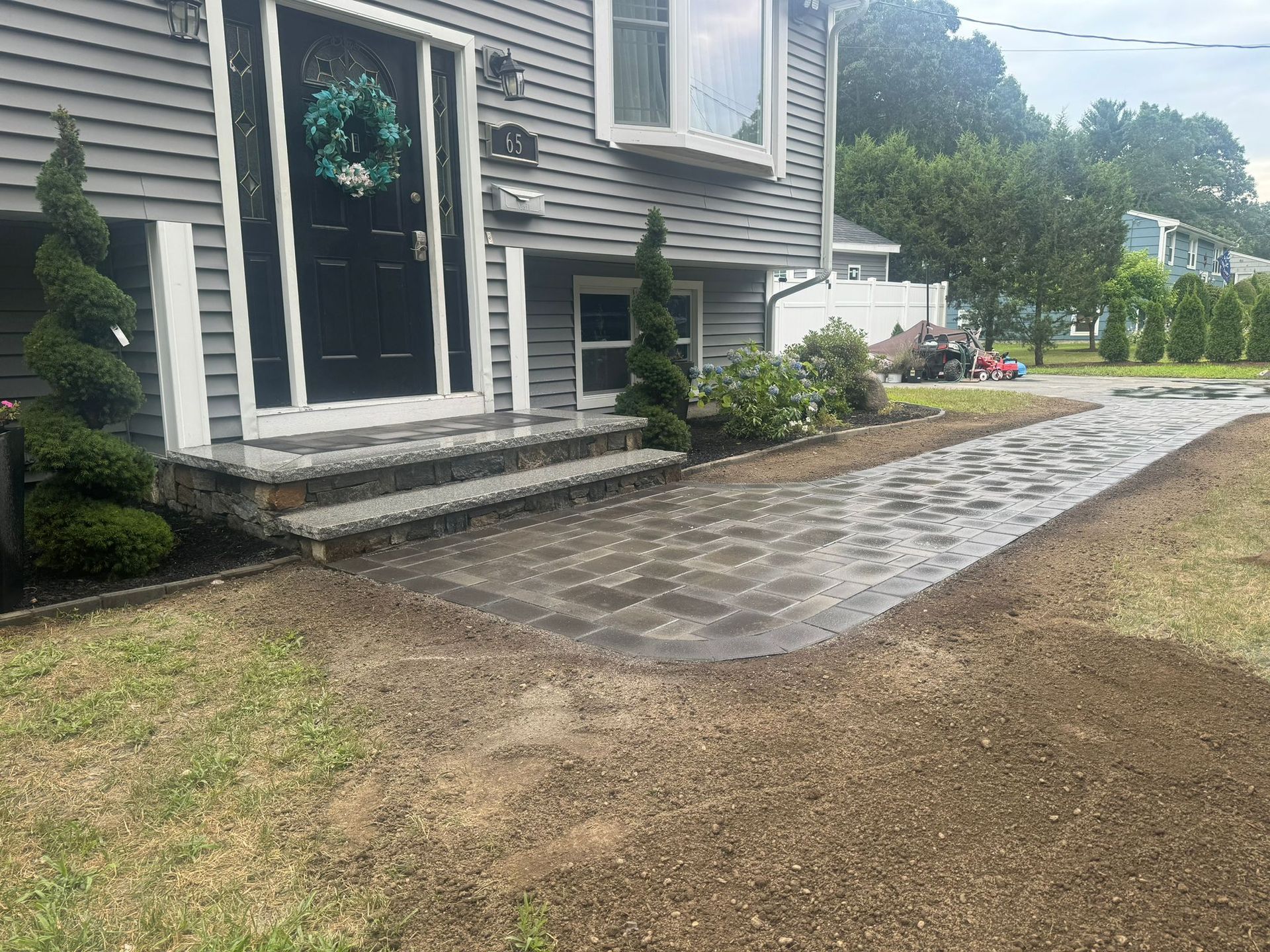 A house with a patio in front of it and a driveway leading to it.