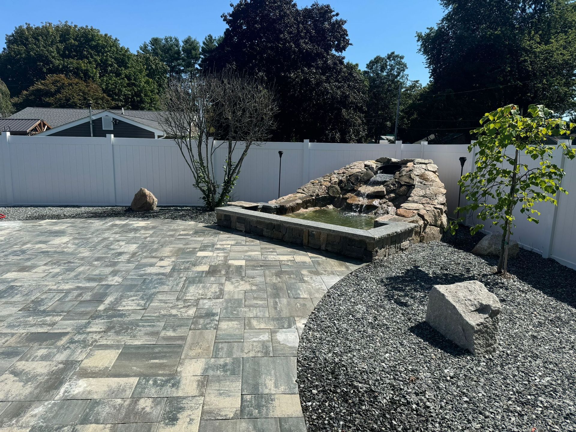 A backyard with a white fence and a waterfall