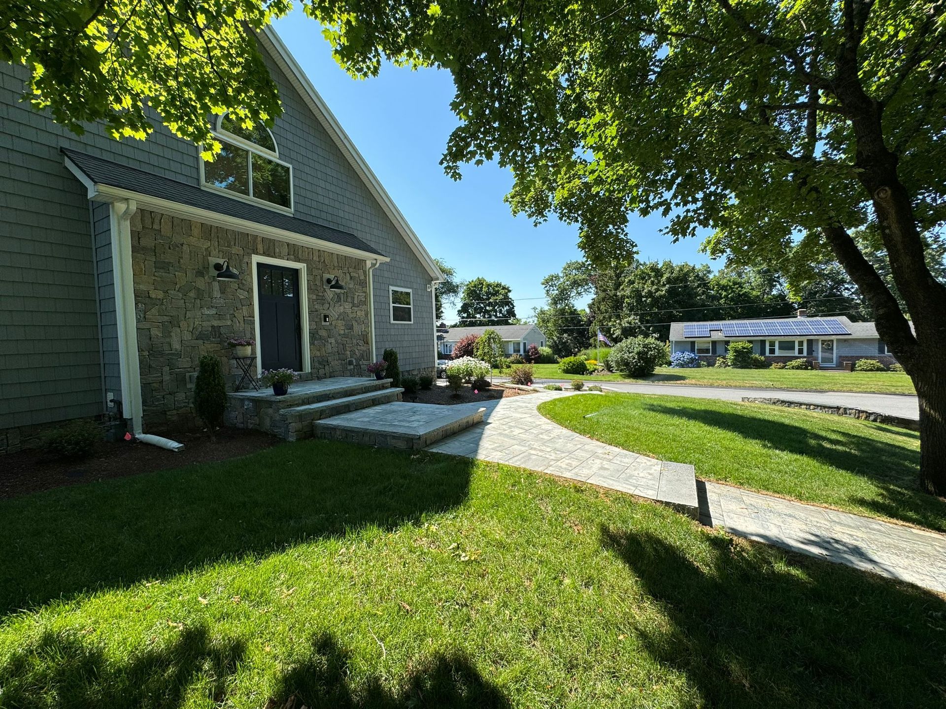A house with a walkway leading to it is surrounded by trees and grass.