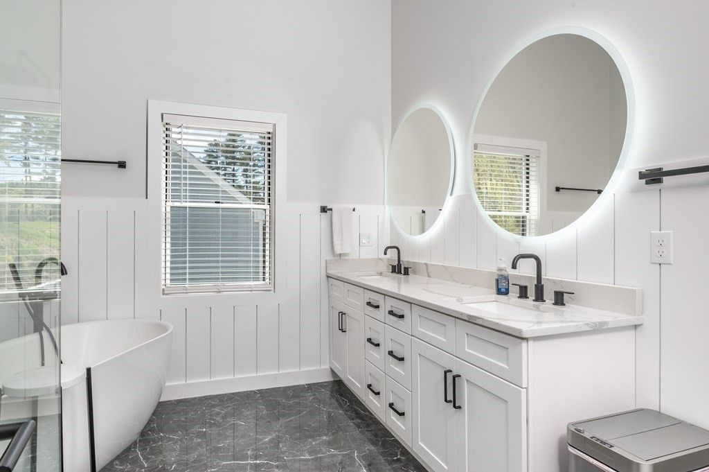 A bathroom with two sinks , a tub , and two mirrors.