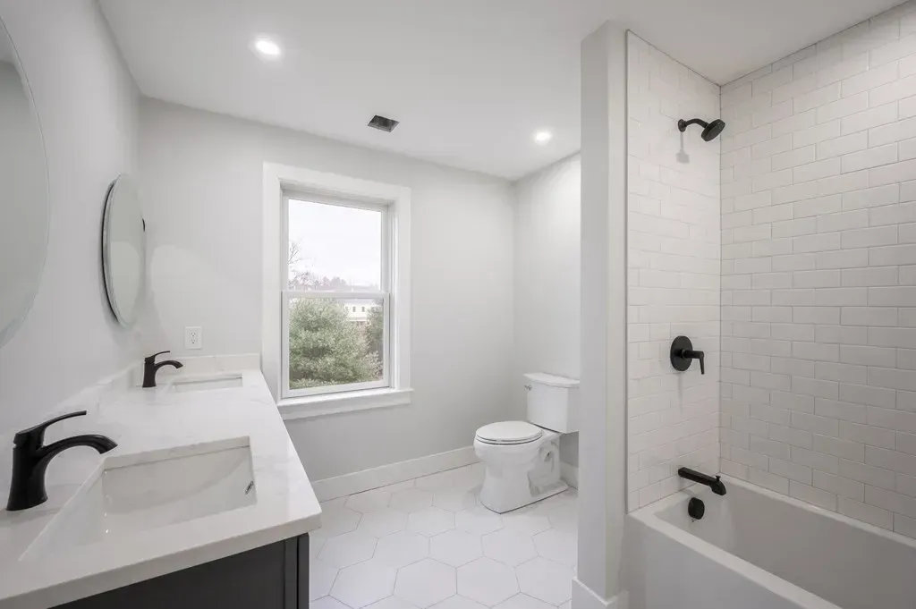 A bathroom with two sinks , a toilet , and a bathtub.