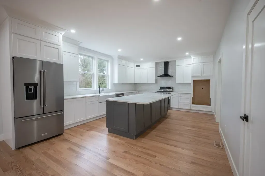 A kitchen with white cabinets , stainless steel appliances , and a large island.