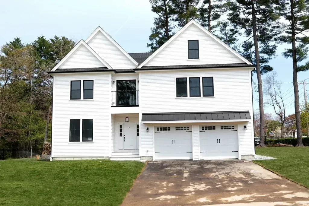 A large white house with three garage doors and a driveway