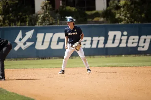 Baseball player in navy uniform standing on infield at UC San Diego stadium