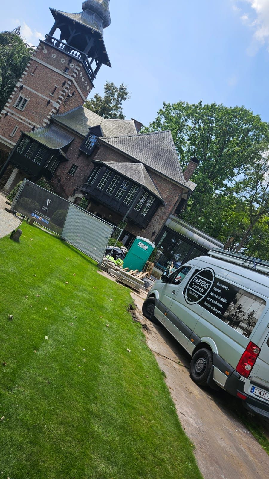 Een wit busje staat geparkeerd voor een groot gebouw.