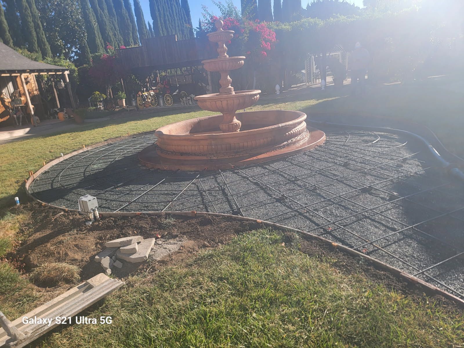 A fountain is sitting on top of a concrete patio in a backyard