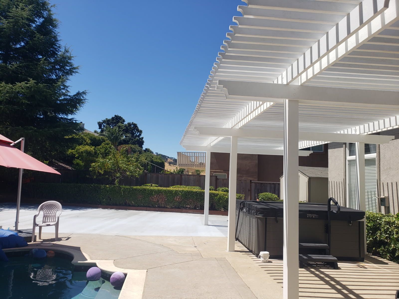 A swimming pool with a hot tub under a pergola