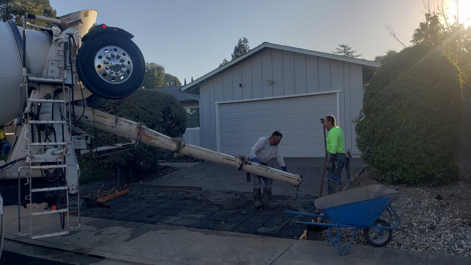 A concrete truck is pouring concrete into a driveway