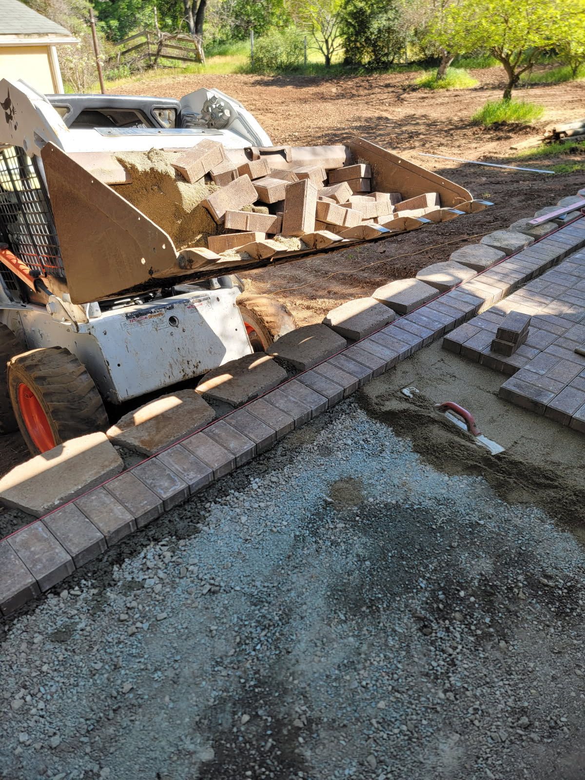 A bobcat is loading bricks into a bucket on a patio