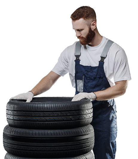 A man is standing next to a stack of tires | Roadrunner Automotive and Diesel Repair, Inc.