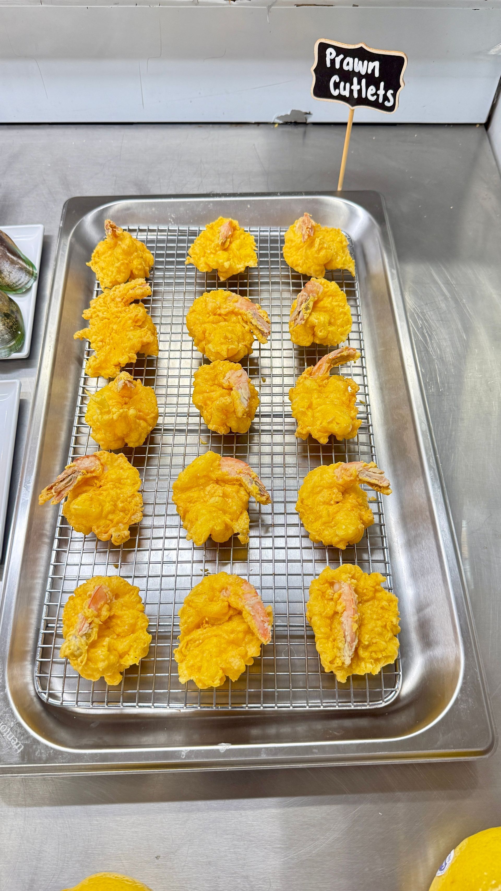 Tray of golden, fried prawn cutlets on a wire rack, labeled