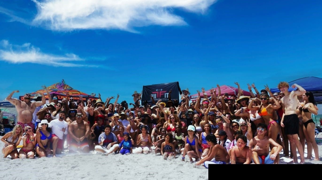 A large group of people are posing for a picture on the beach.
