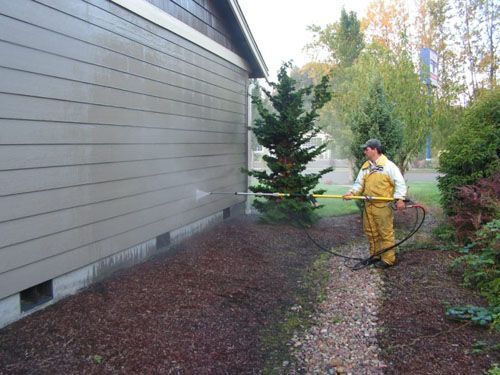A man is spraying a house with a hose