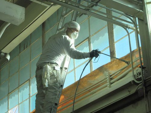A man wearing a mask is spraying paint on a building.
