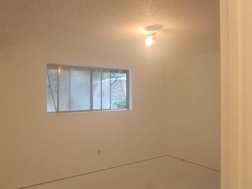 An empty room with a window and a light on the ceiling.