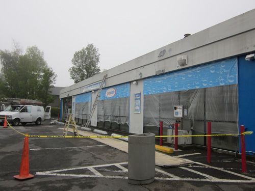 A white van is parked in front of a building that is being painted