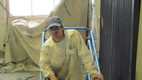 A man wearing a hat and glasses is pushing a cart