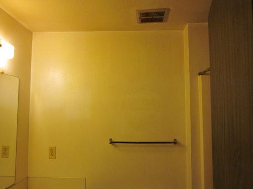 A bathroom with a towel rack and a mirror.