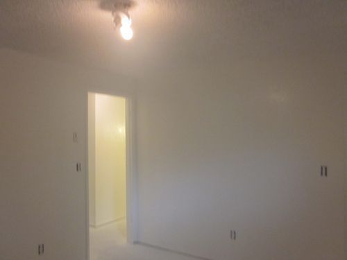 An empty room with white walls and a light on the ceiling.